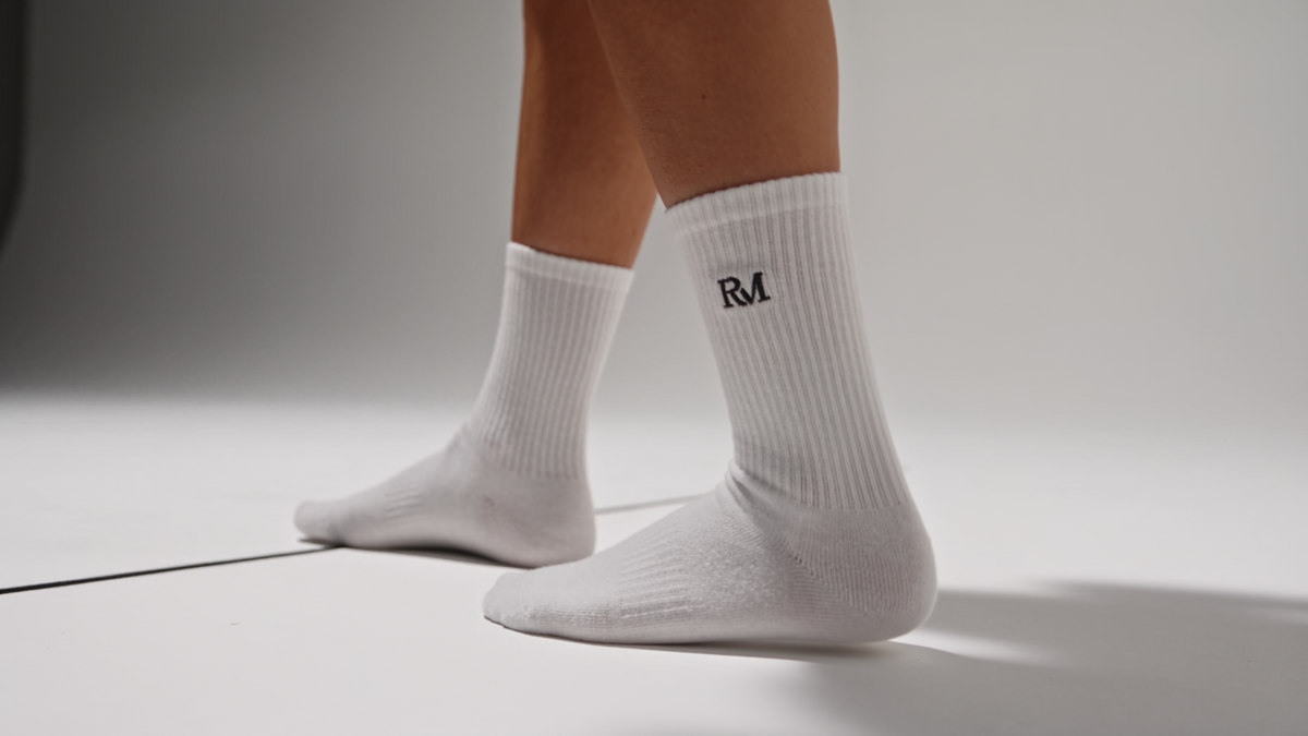 Weiße Tennissocken mit RM-Monogramm, seitliche Ansicht am Model